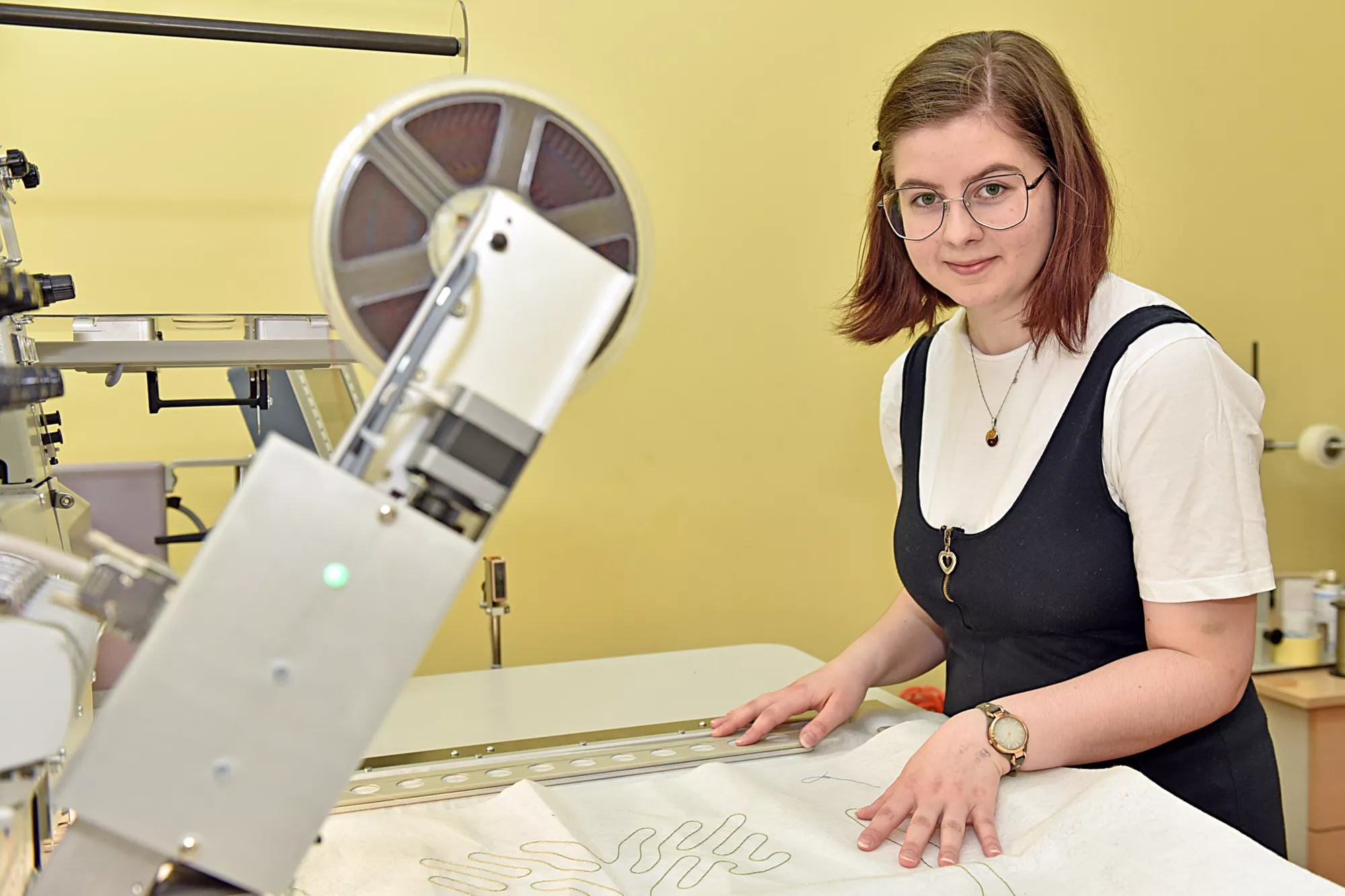 Kobieta obsługuje maszynę włókienniczą.