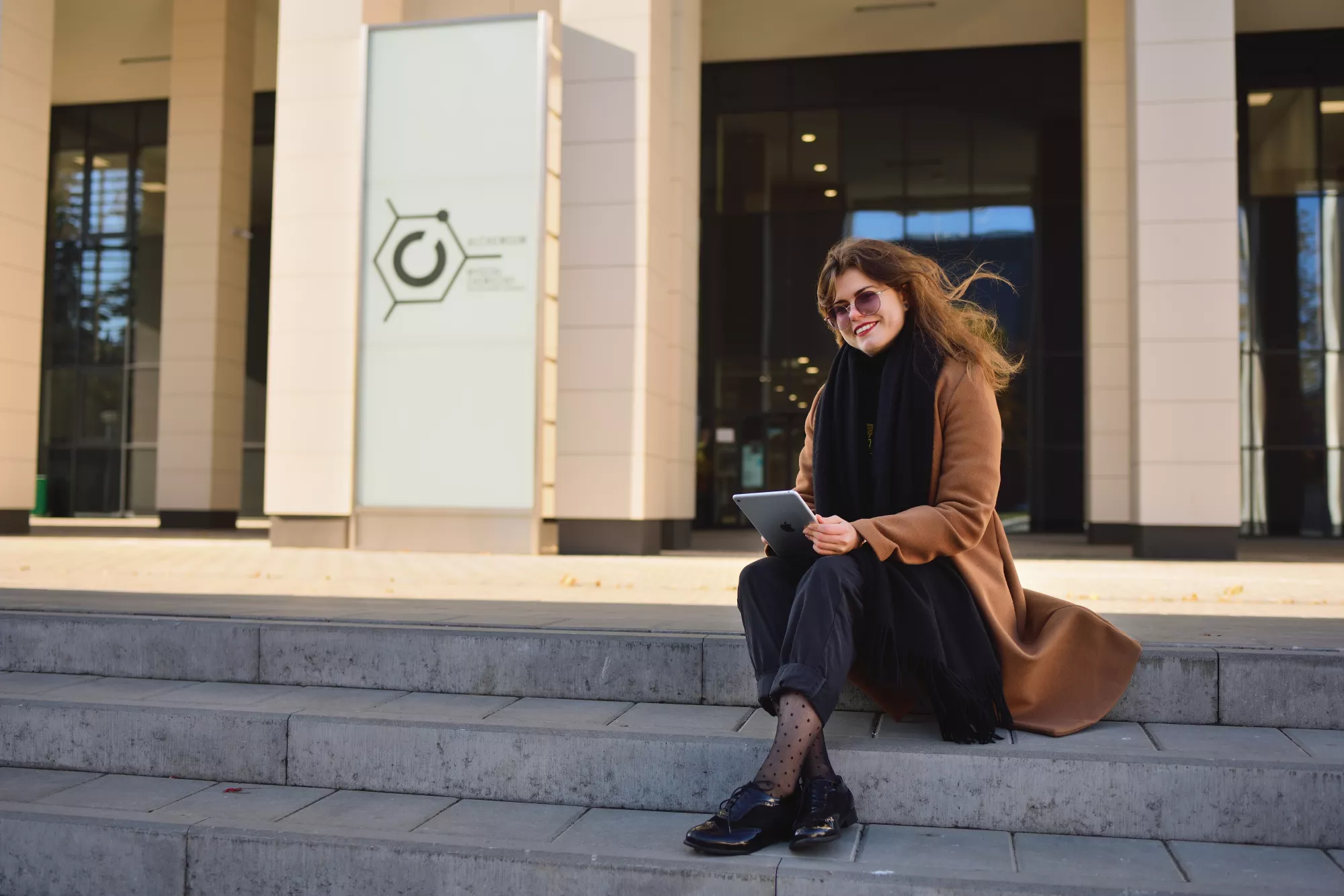Studentka siedzi na schodach przed budynkiem Alchemium.