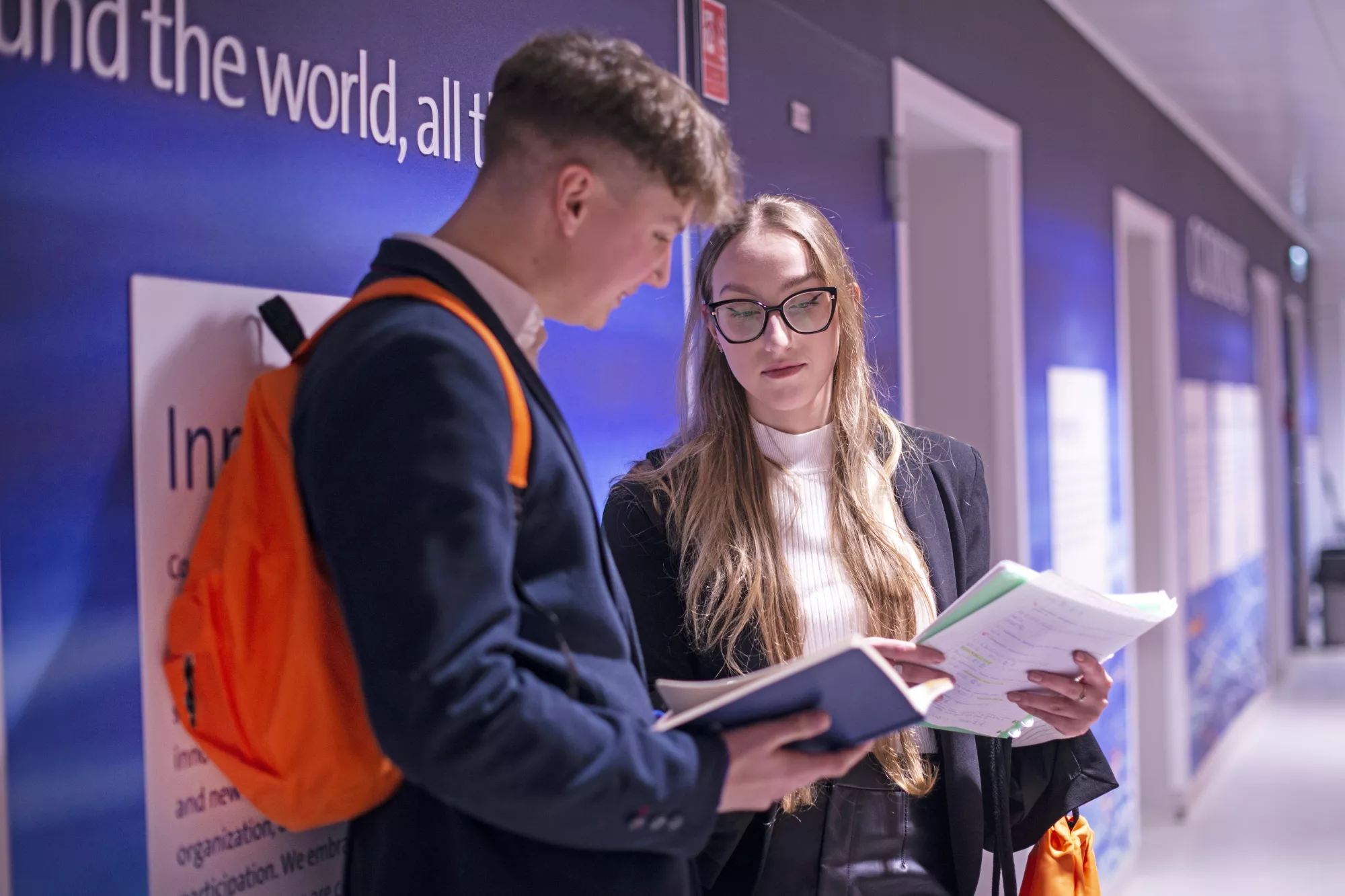 Students standing in the hall and talking. 