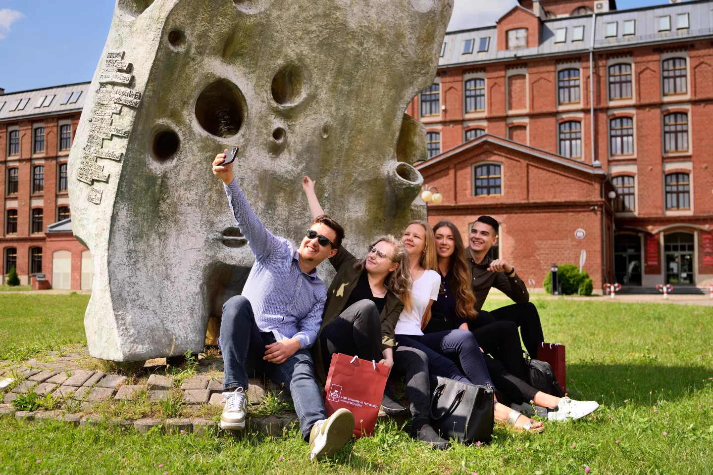 Group of students takes a selfie in front of TUL's building. 