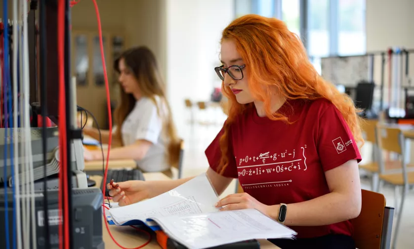 Studentka siedzi przy komputerze i czyta instrukcję do zadania.