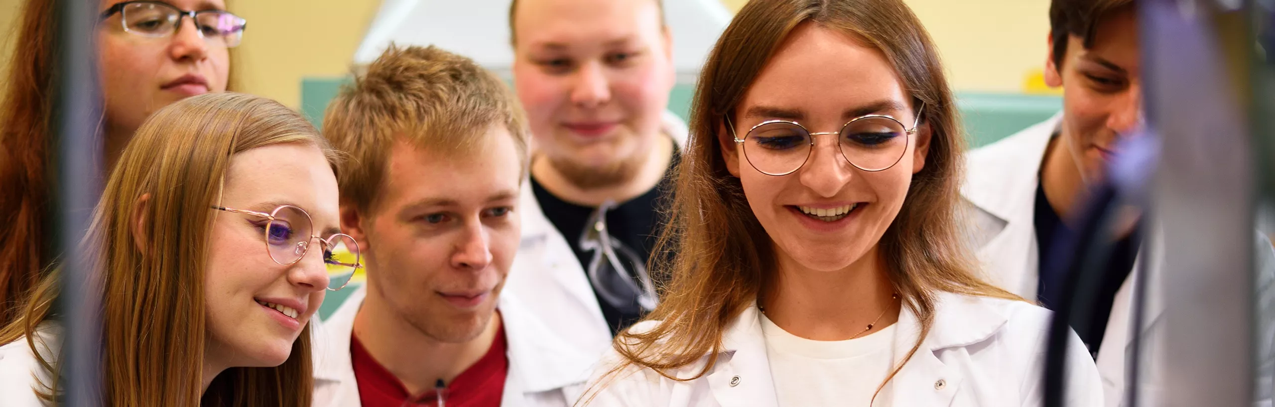 Students stand in lab coats.