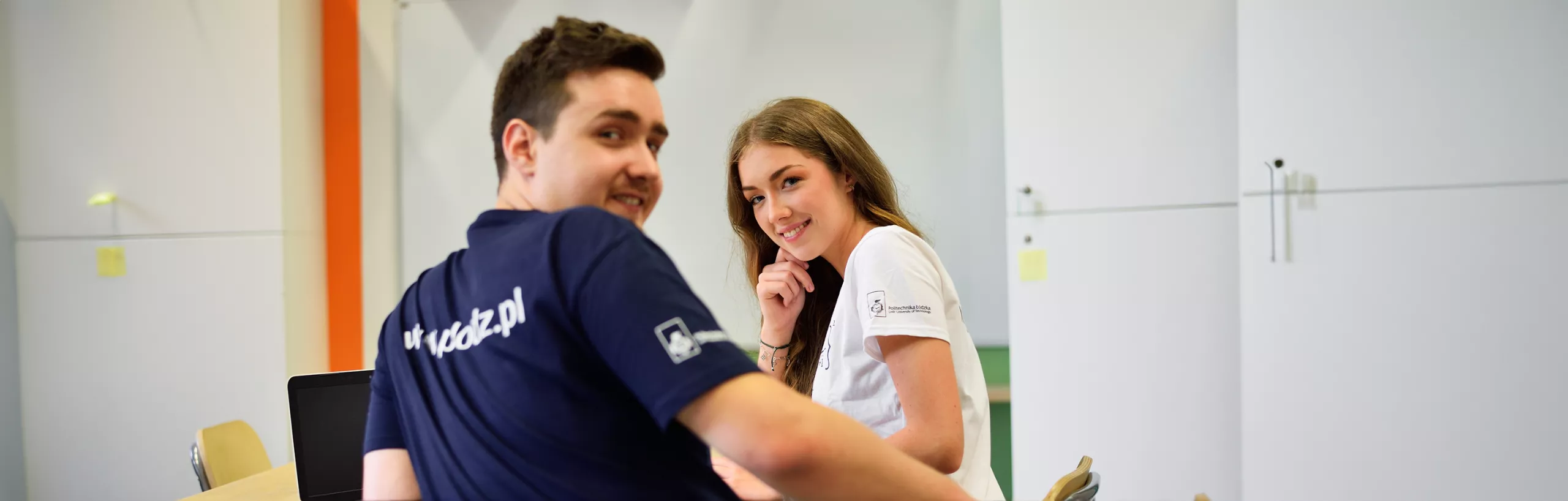 Two students sitting at a table in a lecture room. 
