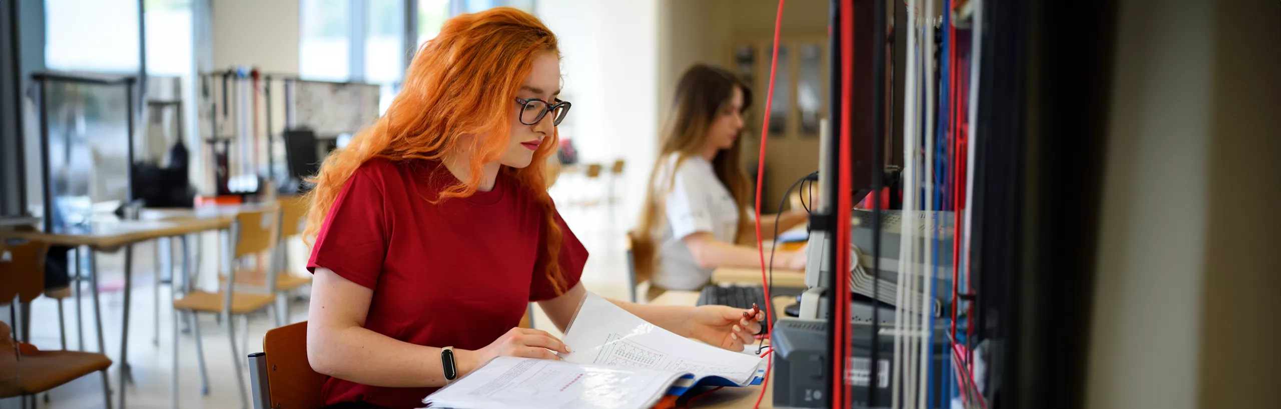 Studentka czyta notatki w sali zajęciowej.