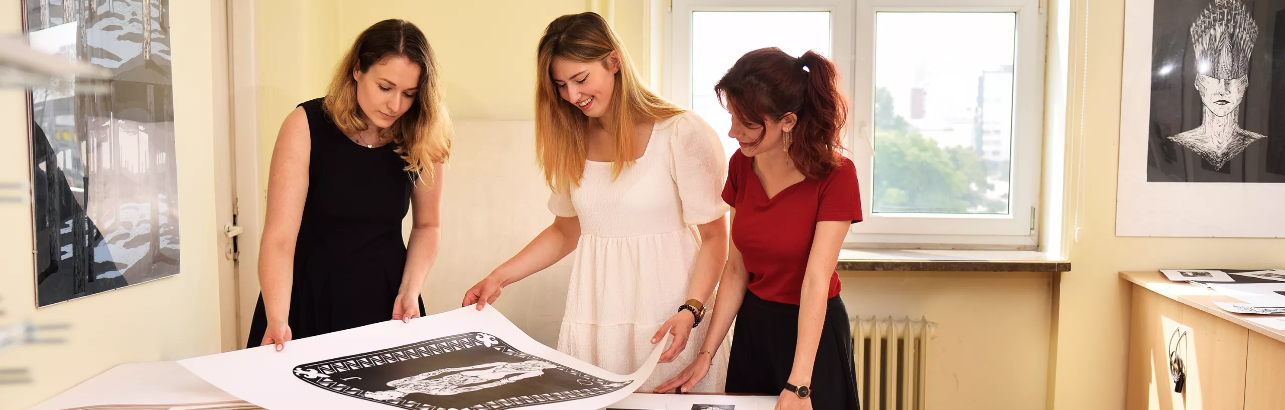 Studentki oglądają  prace plastyczne w pracowni.