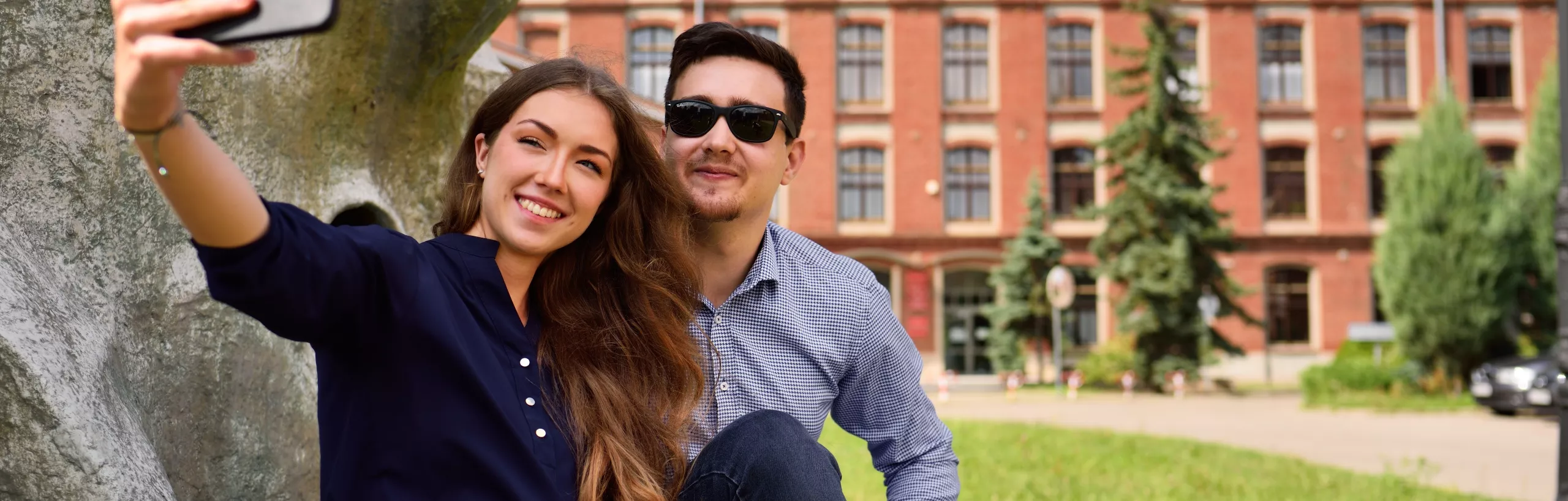 Studenci robią sobie zdjęcie przed budynkiem Politechniki Łódzkiej.