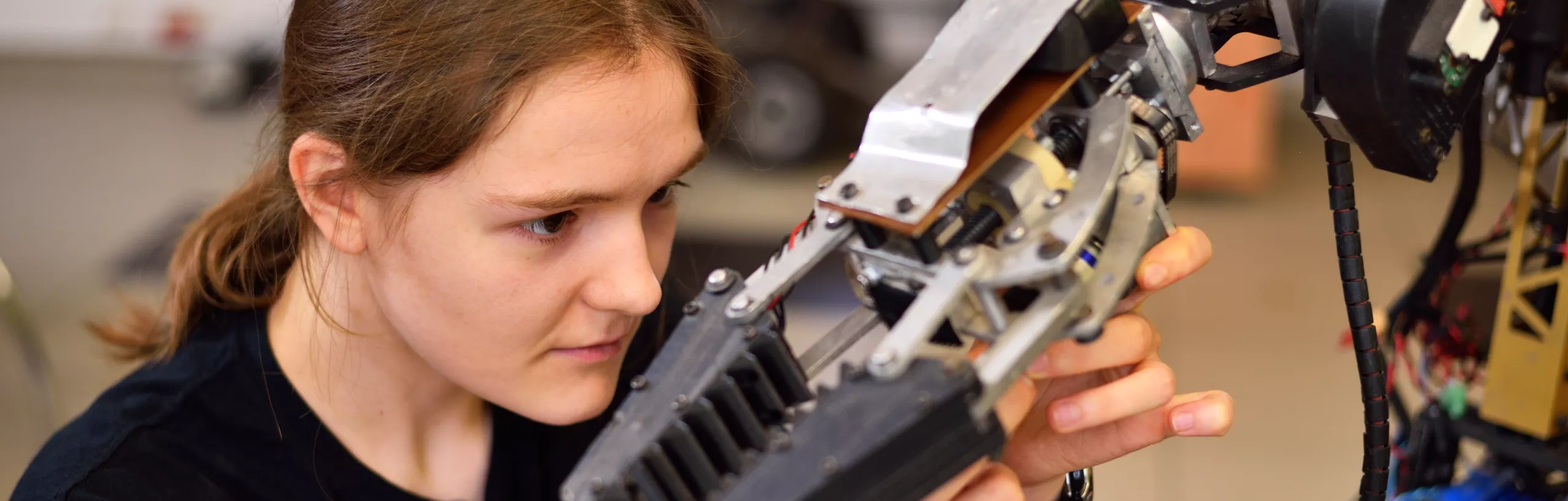 Studentka instaluje ramię robotowi.