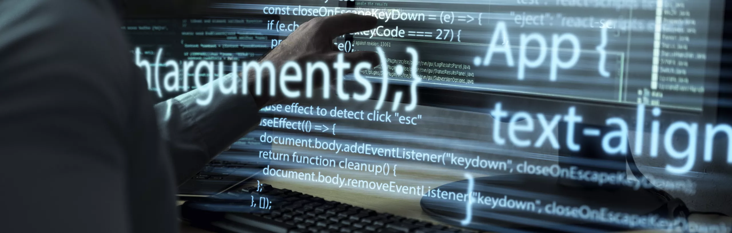 programista przy biurku, pracujący z dużym monitorem